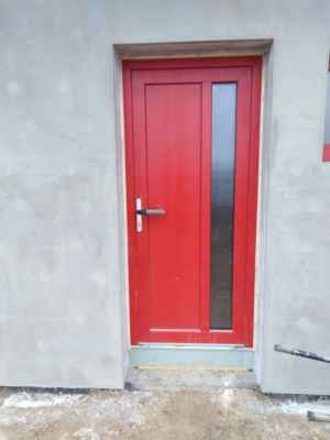 Vchodové plastové dveře s vloženou výplní v červené barvě